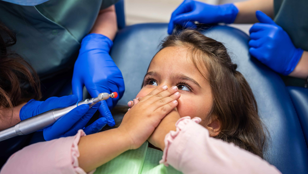 Niña tapándose la boca en el dentista